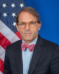 Matthew Posing for headshot in front of an American Flag