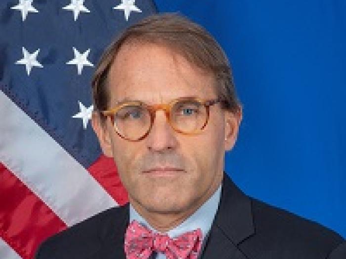 Matthew Posing for headshot in front of an American Flag